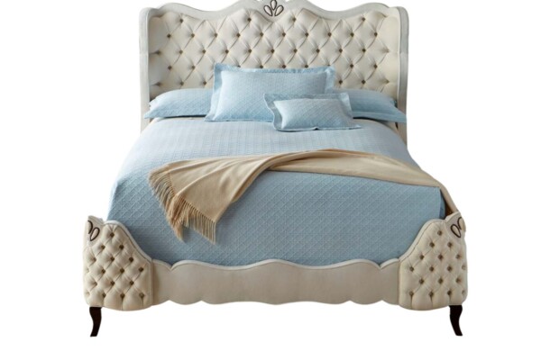 A Cama Estofada Carlisle AD Boutique exibe cabeceira alta em capitonê, moldura clara, estofamento premium e roupa de cama azul.